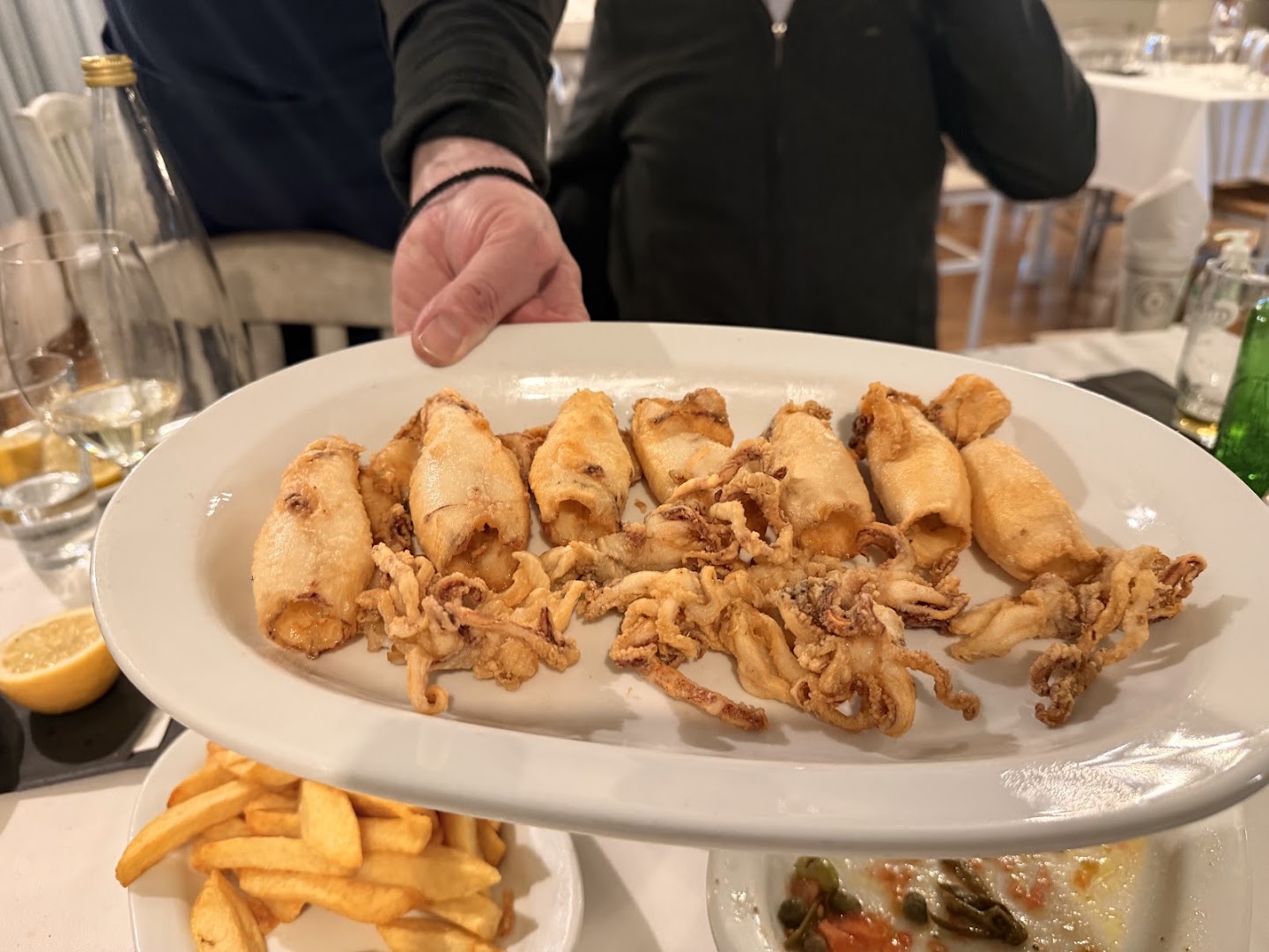 Large platter with grilled seafood dishes and lemon wedges on a taverna table in Kifisia.