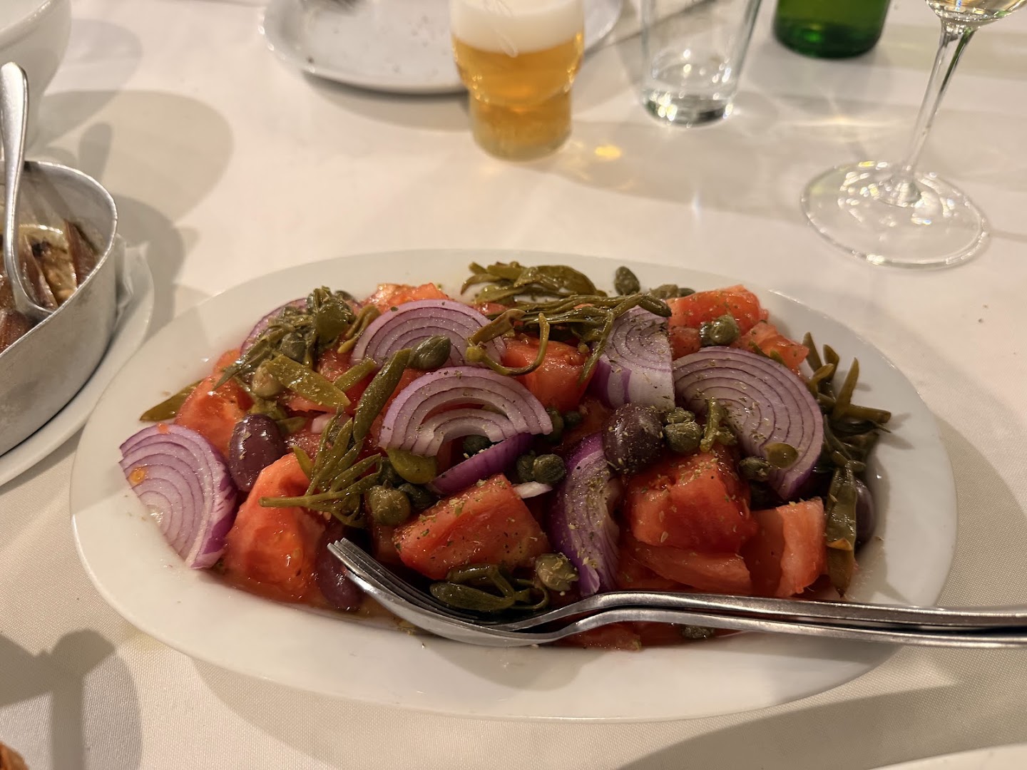 Wine glasses, plates with meze and seafood at a social table.