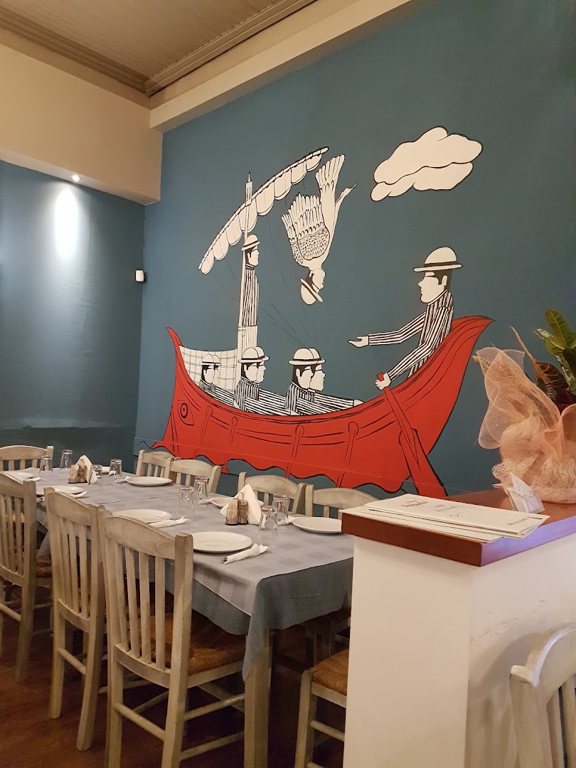 Innendørs område på en tradisjonell sjømat-taverna med dekkede bord og maritim dekor.